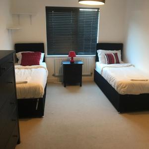 a bedroom with two beds and a red lamp on a table at Executive Brentwood Apartment in Brentwood