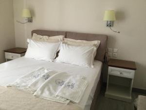 un letto con lenzuola e cuscini bianchi di Kochyli Hotel a Spetses