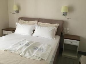 a bed with white sheets and pillows on it at Kochyli Hotel in Spetses