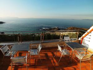 balcone con sedie, tavoli e vista sull'oceano di Hotel Luz de Luna a Portonovo