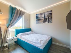 ein Schlafzimmer mit einem blauen Bett und einem Fenster in der Unterkunft Apartament 617 w Hotelu Polonia in Kołobrzeg