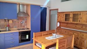 cocina con mesa de madera y armarios azules en Vialunga, en Tuscania
