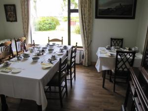 a dining room with a long table with white tablecloths at An Dooneen, The Hurley Farm B&B in Ballydavid