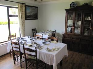 un comedor con 2 mesas con manteles blancos en An Dooneen, The Hurley Farm B&B, en Ballydavid