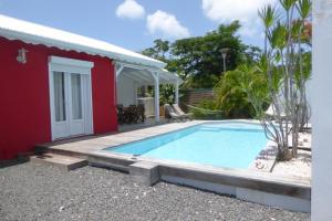 a house with a swimming pool next to a red building at villa bananas in Saint-François