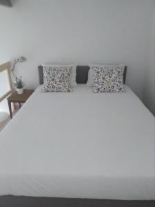 Una cama blanca con dos almohadas encima. en Ilha da Glória - Miragaia, en Oporto
