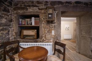 Habitación con mesa y sillas en una pared de piedra. en Casa o Leiteiro, en Dumbría