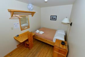 małą sypialnię z łóżkiem i lustrem w obiekcie The Bunkhouse w mieście Dawson City