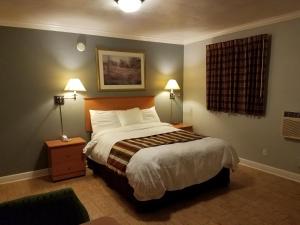 a bedroom with a large bed with two lamps on it at Scottish Inn - Okeechobee in Okeechobee