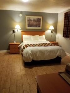a bedroom with a bed and two lamps and a desk at Scottish Inn - Okeechobee in Okeechobee