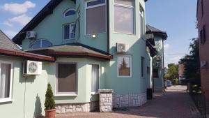 una casa blu e verde su una strada di Guest House Luxotel a Zrenjanin
