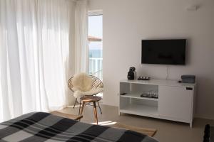 1 dormitorio con TV, silla y cama en Sea Sense Boutique Hotel & Wellness en Sozopol