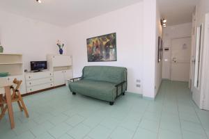 リド・ディ・ポンポーザにあるConchiglia apartmentsのリビングルーム(緑の椅子、テレビ付)