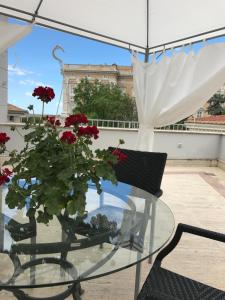 einen Glastisch mit roten Blumen auf dem Balkon in der Unterkunft Mà Maison in Caserta