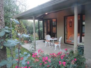 eine Terrasse mit einem Tisch, Stühlen und Blumen in der Unterkunft Oldfields in Geraldine