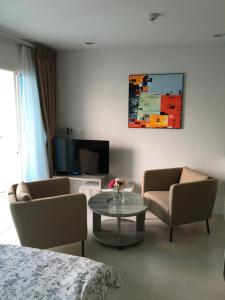salon z 2 krzesłami, stołem i telewizorem w obiekcie Grand Blue Condominium by Nuttaya w mieście Klaeng