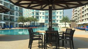a table and chairs under an umbrella next to a pool at Grand Blue Condominium by Nuttaya in Klaeng