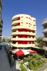 ein Gebäude mit roten und weißen Sonnenschirmen davor in der Unterkunft Hotel Esperia in Alba Adriatica