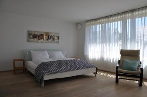 een slaapkamer met een bed en een stoel bij Ferienwohnung Fischbach in Friedrichshafen