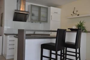 una cocina con barra y 2 taburetes negros en Ferienwohnung Fischbach, en Friedrichshafen 6 fotos más