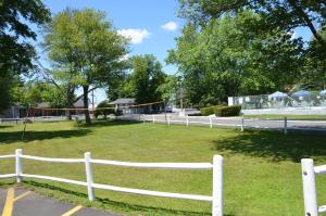a white fence in front of a field with trees at Beachway Motel in Salisbury