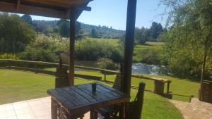 a wooden bench sitting under a gazebo near a river at Thandamanzi Self Catering in Sabie