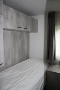 a bedroom with a white bed and a window at Chalet de Schelp in Domburg