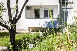 a window in a white house with grass and weeds at Apartments Lovor in Split
