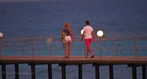 een man en een vrouw die op een pier lopen bij Wadi Lahmy Azur Resort - Soft All-Inclusive in Abū Ghuşūn