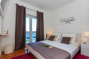 a bedroom with a large white bed with a window at Ante Apartments in Podstrana