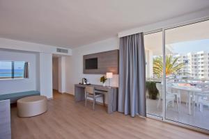 a living room with a desk and a room with a view at Aparthotel Playa Dorada in Sa Coma