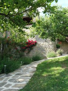 a garden with a stone pathway and red flowers at Apartmani Damiani in Grožnjan