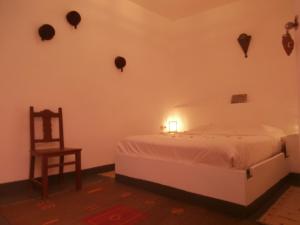 um quarto com uma cama, uma cadeira e um candeeiro em Maison Xanadu em Sidi Ifni