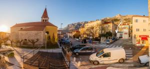 uma cidade com carros estacionados numa rua com uma igreja em Apartments Antonio em Makarska