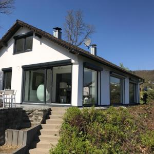 een wit huis met grote glazen deuren erop bij See-Oase Rurberg in Rurberg