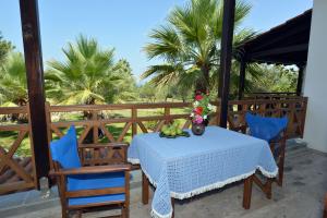 a table and chairs on a porch with palm trees at Haus Katerina in Vourvourou