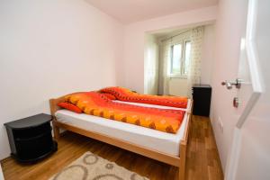 a bedroom with a bed with orange sheets and a window at Apartment Ilidža in Sarajevo