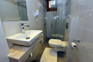 a white bathroom with a sink and a toilet at Haus Katerina in Vourvourou