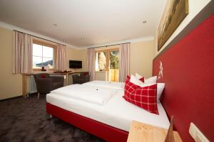ザンクト・アントン・アム・アールベルクにあるHotel Garni Rauchの赤い壁のベッドルーム1室(大型ベッド1台付)