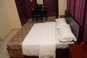 a large bed in a bedroom with a table at Diamonds Hotel Kampala in Kampala