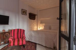 um quarto com uma cama e uma cadeira vermelha em Riad Zebrakaro em Marrakech
