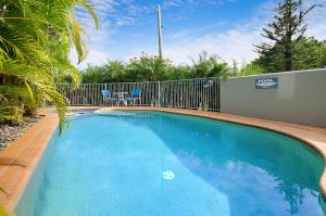 a large blue swimming pool next to a fence at Reflections Holiday Apartments in Maroochydore