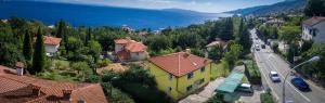 een geel huis op een heuvel naast een weg bij Villa Melita in Opatija