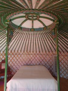 Bett in einer Jurte mit Decke in der Unterkunft Drome esprit nature in Le Poët-Célard