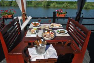 einen Tisch auf einem Boot mit Essen und Wein in der Unterkunft Lacul Racilor in Olimp