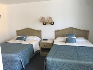 a bedroom with two beds and a lamp on the wall at Cape Harbor Motor Inn in Cape May