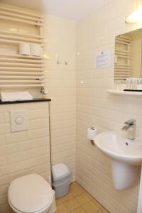 La salle de bains est pourvue de toilettes blanches et d'un lavabo. dans l'établissement Havenhotel Texel, à Oudeschild