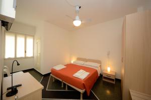 a bedroom with a bed with an orange blanket and a desk at Locanda Marita in Finale Ligure