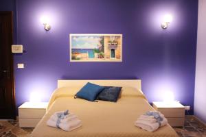 Un dormitorio con paredes moradas y una cama con toallas. en B&B President Palace, en Riposto