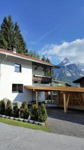 a white building with a balcony and mountains in the background at Ferienhaus Stricker in Ehrwald